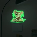 Adesivo da parete fluorescente con topolino che legge accanto a un interruttore luce - Luce Verde (11x13cm)
