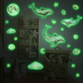 Dettaglio di adesivi murali luminosi con delfini e luna che brillano nella camera scura - Bagliore Verde (MG-YP019)