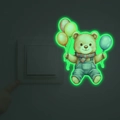 Leuchtender Wandaufkleber mit niedlichem Cartoon-Bär und Ballons, der grün am Lichtschalter glüht - Grün
