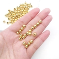 Polished gold round spacer beads for DIY jewelry held in hand to show 3mm to 6mm size - Round Bead (15850)