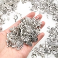 Hand holding assorted silver alloy DIY pendants with tree of life and angel charms - Random 20 Pieces Antique Silver Pendants