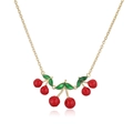 Detailed view of red cherry pendant with green leaves and golden chain on white background - Gold Red Cherry Necklace