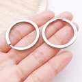 Close-up of flat silver alloy key rings held by hand for DIY keychain accessories - Steel Color 30 Round Flat Stainless Steel Keychain (30x30mm-10180)