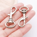 Close-up of polished silver metal swivel lobster clasps held in hand for size reference - White K Gun Clasp Keychain (17x40mm-13024)