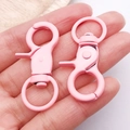 Detail van twee roze matte karabijnsluitingen met draaibare basis voor DIY-sleutelhangers - 44x21mm / Roze