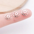 Macro shot of three silver hollow flower bead caps on a fingertip showing tiny scale - 7mm / Bright Silver