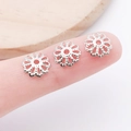Silver hollow flower bead caps for DIY jewelry making shown in small size on finger - 7mm / Silver