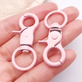 Roze matte karabijnsluiting met draaibare ring getoond in de handpalm - 44x21mm / Lichtroze