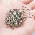 Polished silver jump rings for DIY jewelry and keychain making held in hand for scale - White K Iron Round Jump Rings (1.2x8mm-12985)