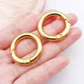 Hand holding two golden spring O-ring alloy buckles for handbags and jewelry DIY - 28mm / KC Gold