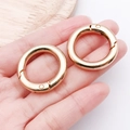 Pair of gold alloy spring O-rings in palm showing scale and shiny metallic finish - 28mm / KC Gold