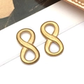 Close-up of matte gold infinity symbol earrings placed on vintage magazine pages - Infinity Symbol Connector (T2845)