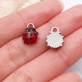 Pendentifs coccinelle en émail rouge pour bijoux DIY montrés sur un doigt - Mini Coccinelle Émail Rouge Argenté