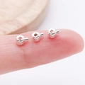 Versilberte Quetschperlen aus Kupfer für DIY-Schmuck auf einer Fingerspitze als Maßstab - Flach (19157) / Hellsilber