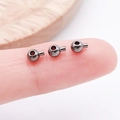 Drei gun-schwarze Kupfer-Crimp-Perlen für DIY-Schmuck auf einer Fingerspitze - Rund (25907)