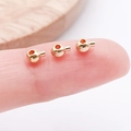 Winzige goldene Messingperle für DIY-Schmuck auf einer Fingerspitze gezeigt - Rund (26048)