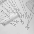 Dettaglio di pendenti a lettera argentati con zirconi su catena di perle decorata - Lettera A / Argento