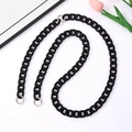 Detail van een glanzende zwarte acryl crossbody ketting met een zilveren metalen veerring - Lichtzwart