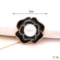 Macro shot of vintage black enamel camellia brooch with gold edges and pearl detail - Small Pearl Flower