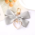 Détail de porte-clés nœud en satin gris avec pendentif cœur perlé et fermoir doré - Gris