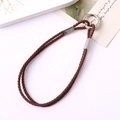 Close-up of dark brown woven leather phone strap with silver metallic ring and clasp - Tan