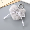 Detail view of a plush heart keychain featuring a pearl bow and a silver metal ring - Light Gray