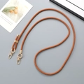 Detail of adjustable brown braided leather strap with gold hardware on blue background - Tan