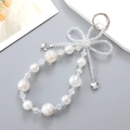 Detail of beaded phone charm with crystal bow, gold-foil pearls and butterfly pendants - White