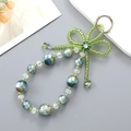 Detail of beaded phone charm with blue gradient beads and green crystal bow design - Green