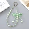 Mint green beaded phone charm with crystal beads and 3D bowknot on grey background - Green