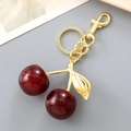 Detailed view of red resin cherry keychain with glitter and golden alloy hook - Black Red