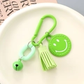 Close-up of bright green smiley face keychain with suede tassel and metal bell - Green