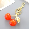 Exquisite cherry keychain bag charm with bright red resin fruits and gold leaf finish - Orange