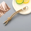 Close-up of khaki hand-woven nylon rope keychain with silver spring carabiner hook - Khaki