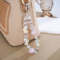 Detail of luxury crown crystal beaded keychain hanging on a khaki leather bag - Pink