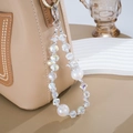 Detail of luxury crystal beaded phone charm with crown ornament hanging on a bag - White