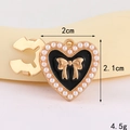 Detailansicht eines herzförmigen Anhängers mit schwarzer Emaille und weißen Perlen - D3157 Kragenknopf Mit Perlenschleife Und Herzform (goldfarbener Sockel Schwarz) / Kragennadel