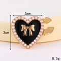 Makroaufnahme einer 3cm Herz-Brosche mit Perlenrand und goldener Schleifenverzierung - D3159 Kragenknopf In Herzform Mit Perle (goldfarbener Sockel Schwarz) / Kragennadel