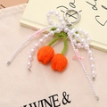 Macro view of hand-knitted orange tulips with white pearl beads and pink silk bows - Orange