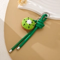 Detailed macro view of handmade crochet kiwi bag charm with green leather strap and metal ring - Green Cord