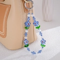 Detail of floral beaded phone strap with blue glass flower beads hanging on a beige leather bag - Blue