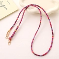 Detailed shot of ethnic woven phone strap with colorful patterns and gold spring buckles - Pink