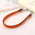 Close-up of orange leather bag strap with silver metal hooks on a white textured surface - Cross Pattern Leather Hand Chain / Orange