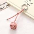 Detail of pink hand-woven leather ball keychain with silver metal ring on white fabric - Korean Pink Braided Ball (K5243)