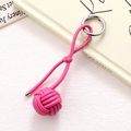 Detail of rose red braided leather ball keychain with silver spring clasp on book - Rose Red Braided Ball (K5246)