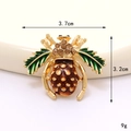 Macro della spilla a forma di ape con ali in smalto verde e strass marroni con misure - Design Ape (D3278) / Ape Ananas (Base Oro)