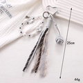 Macro detail of candy bead charm with bow pendant and woven tassels on white background - Silver