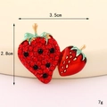 Dettaglio della spilla a fragola con strass rossi e foglie verdi di 3,5 cm x 2,8 cm in macro - Doppia Fragola in Strass (Base Dorata)