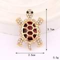 Dettaglio di una spilla a tartaruga dorata con pietre rosse e cristalli bianchi su vassoio - Base Oro Tartaruga Diamanti Rosso (D3301)