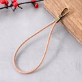 Pink leather wrist strap phone chain with bronze metal lobster clasp on stone surface - Charm / Vintage Cowhide Pendant Light Brown
